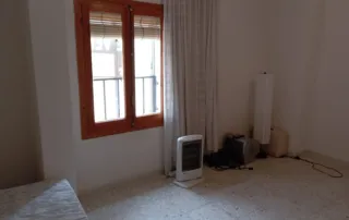 habitación sin amueblar con paredes blancas, un suelo de baldosas y una ventana de madera