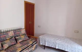 una habitación con un sofá cama, una cama individual y un armario.