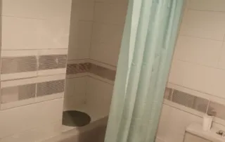 baño con una bañera, una cortina de ducha de color azul verdoso y un inodoro