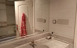 un cuarto de baño con un lavabo, un espejo grande, una bañera y una toalla colgada en la puerta