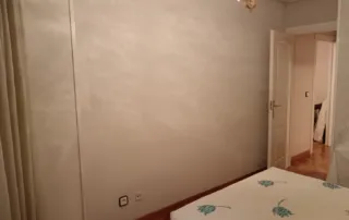 dormitorio presenta un diseño que se centra en una estética de colores neutros, con un acabado de pared texturizado distintivo