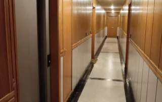 un pasillo interior con paredes revestidas de paneles de madera y un suelo de mármol