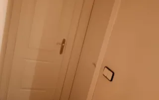 pasillo con tres puertas, probablemente en el interior de una vivienda. La puerta más cercana tiene un tirador negro, mientras que la otra visible tiene un tirador de color claro